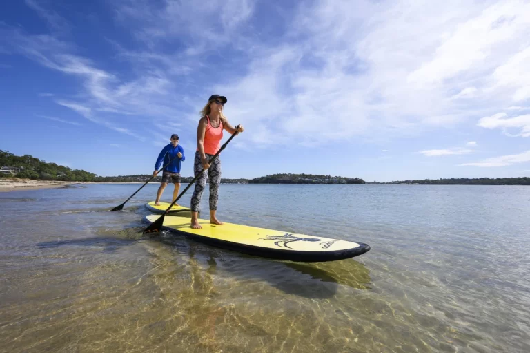 people paddle boarding along the beach at Bundeena